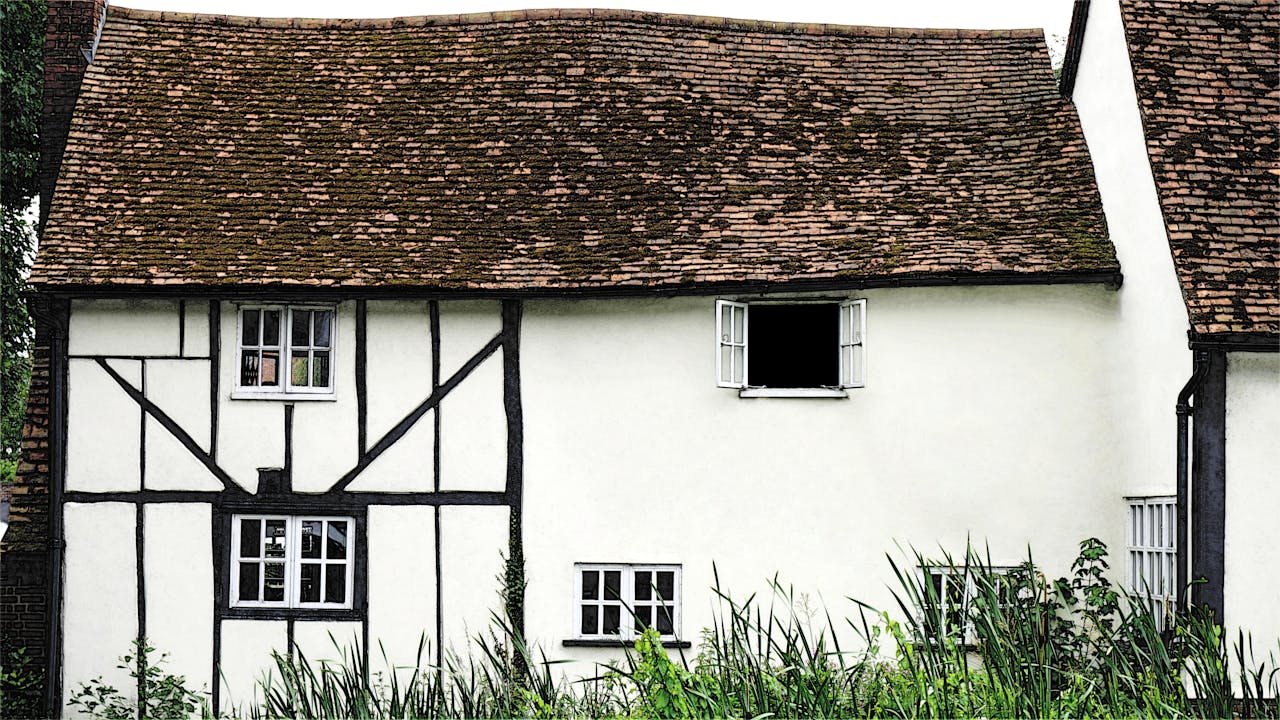 Traditional Tudor-style cottage with white walls and wooden beams, ideal for real estate content.